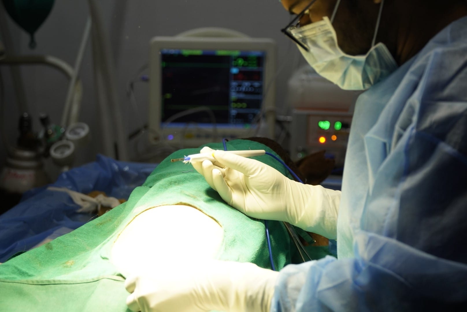 Veterinary surgeon performing renal surgery on a dog using advanced monitoring and electrocautery equipment.